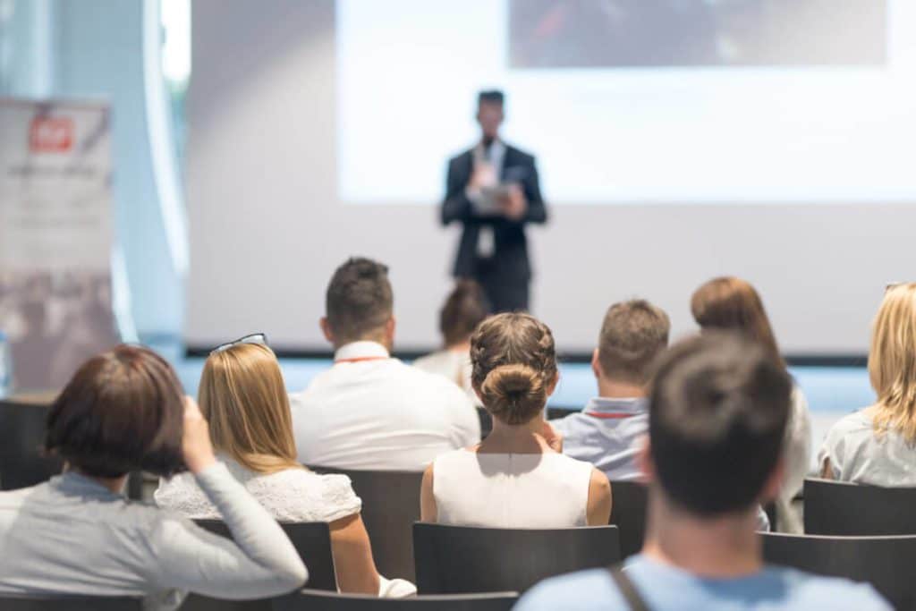 People listening to a talk at a conference, shown from behind