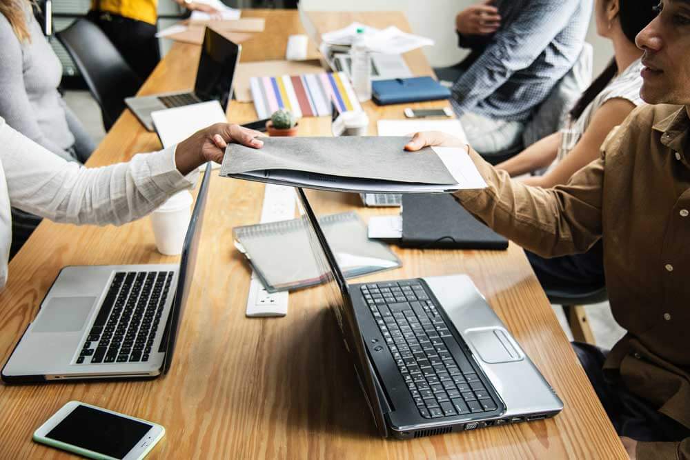 People working with laptops sat along a shared table