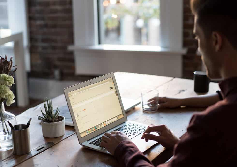 Man using laptop on wooden table in office