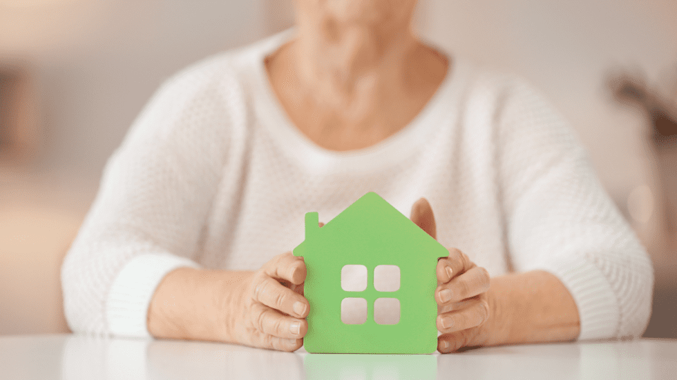 An old lady holding a cardboard house icon