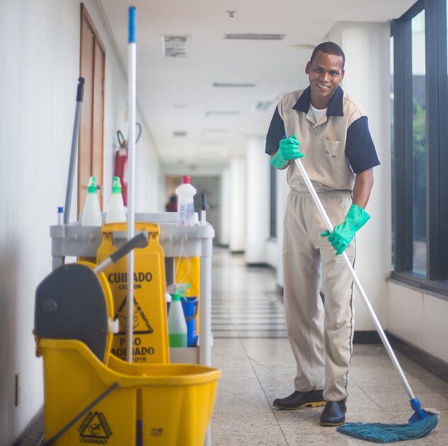 A janitor cleaning the hallway of a large building