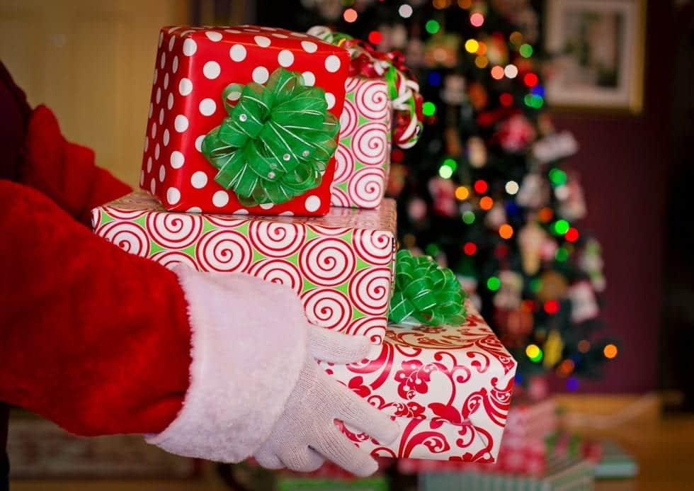 Person dressed as Santa holding Christmas gifts