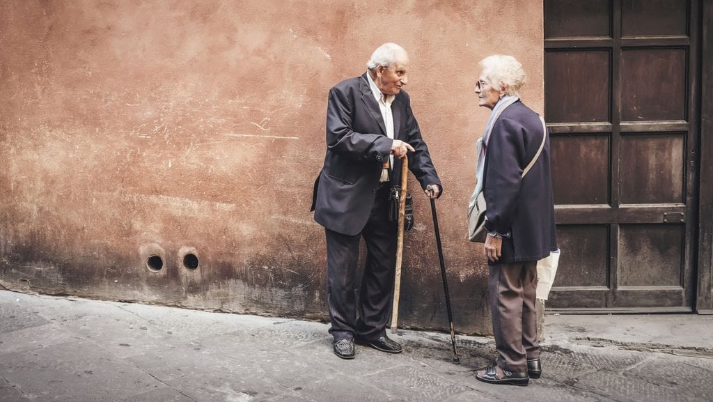 An elderly man and woman standing in an empty street